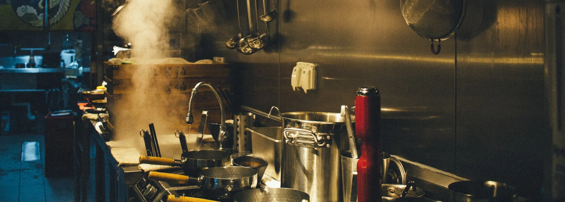 Commercial kitchen with an assortment of pots, pans and utensils with a free-flowing sink.