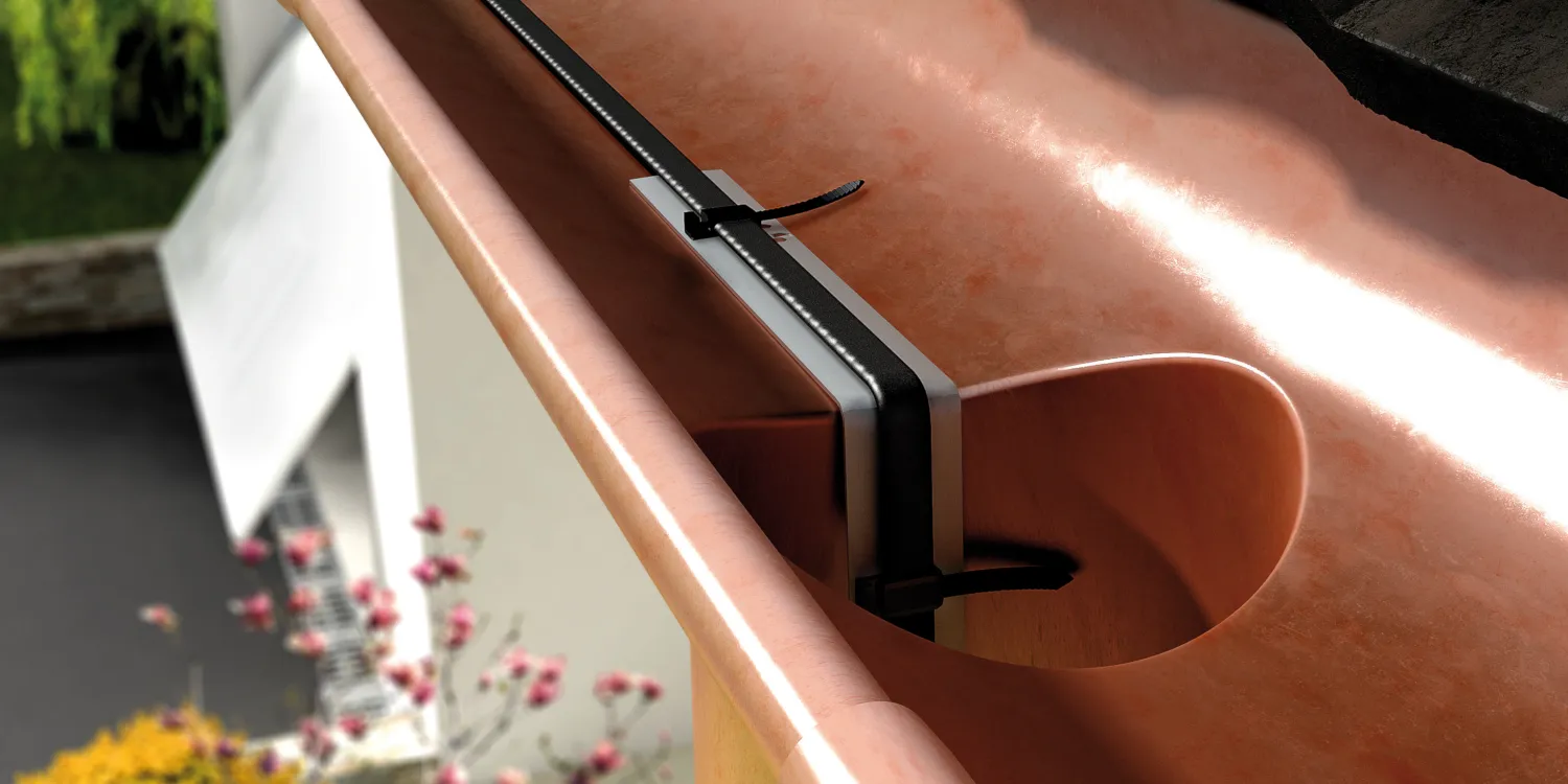 A U-shaped gutter with GM-2X cable running through and down a drain pipe.